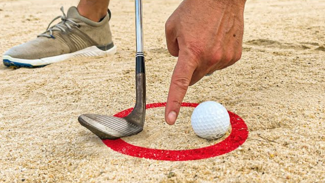 Sand splashing out of a bunker as the ball is lifted clear