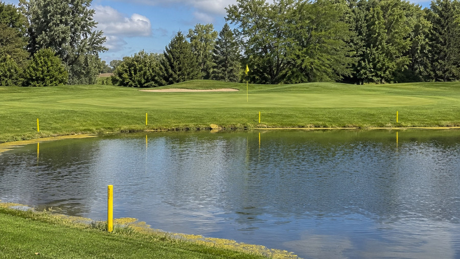 Yellow stakes marking a pond in front of a golf green